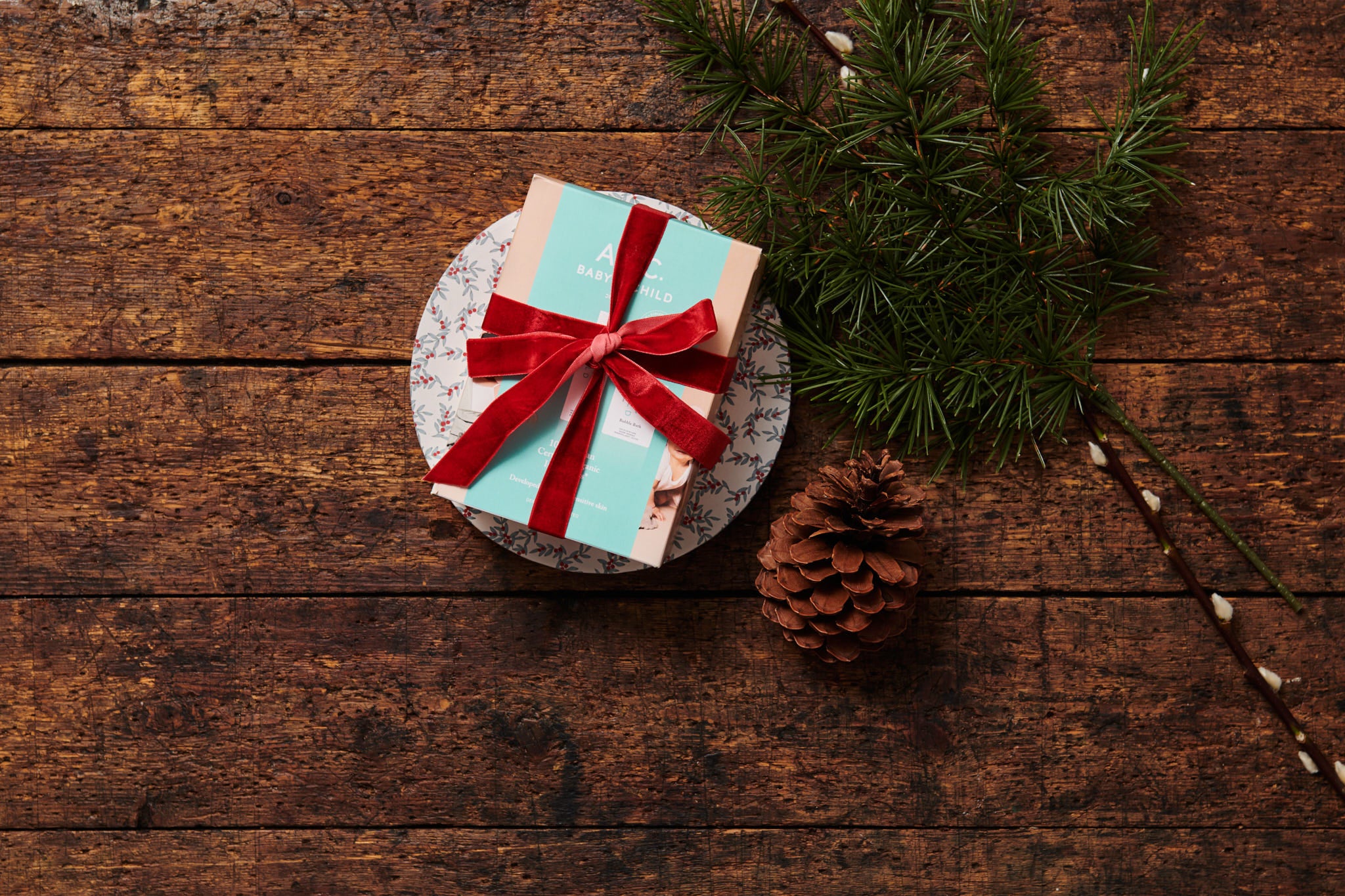 ARC gåvoset som julklapp med rött snöre bredvid en kotte och grankvist